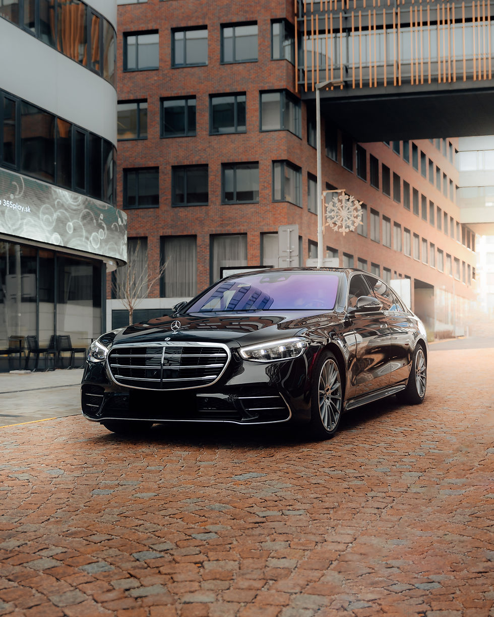 Siyah Mercedes S-Class lüks sedan, şehir içinde parke taşlı yolda, hafif yandan çekim, dikey (portrait) kadraj.