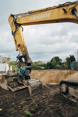 Excavators on a construction site, with dirt and gravel in the background.