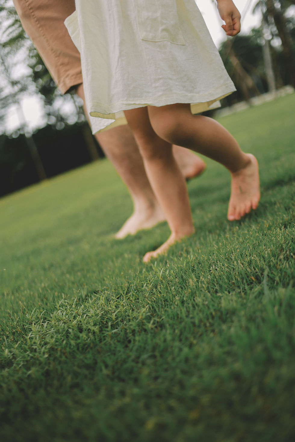 Bare feet walking across soft green grass in sunlight, reflecting a simple moment of connection with the Earth beneath us.