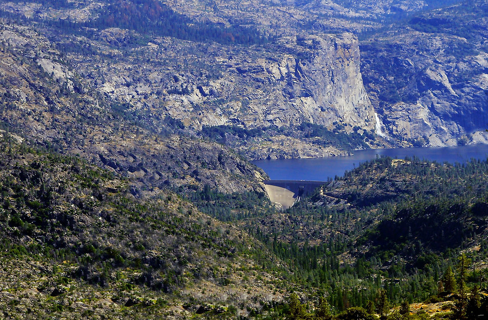 blue lake blocked by dam surrounded by grey cliffs