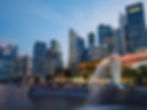 Merlion statue spouting water at dusk in Singapore, with a bustling crowd and lit skyscrapers in the background. Calm, urban evening scene screaming Top 5 AI Startups and Tools in Singapore