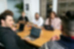 A diverse group of individuals sitting around a conference table and demonstrating Decision Making by Consensus