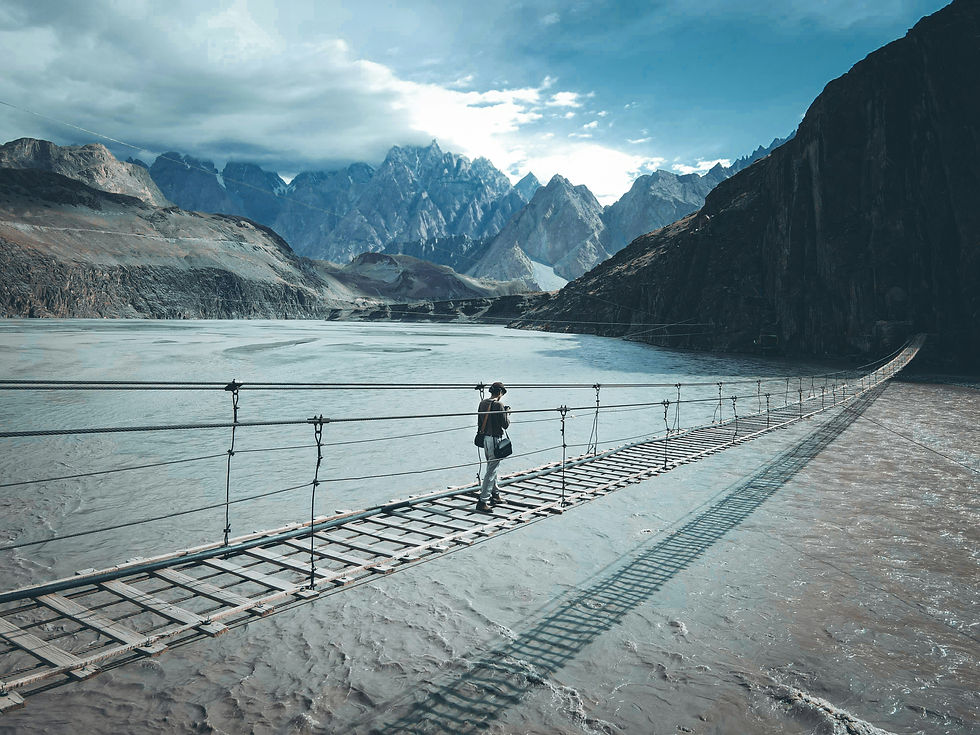 Person walking over bridge through mountains.