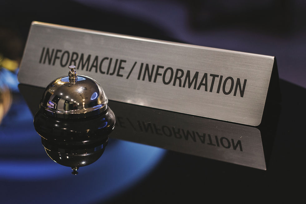 Hotel information bell beside a sign reading INFORMACIJE / INFORMATION on a dark glossy counter.