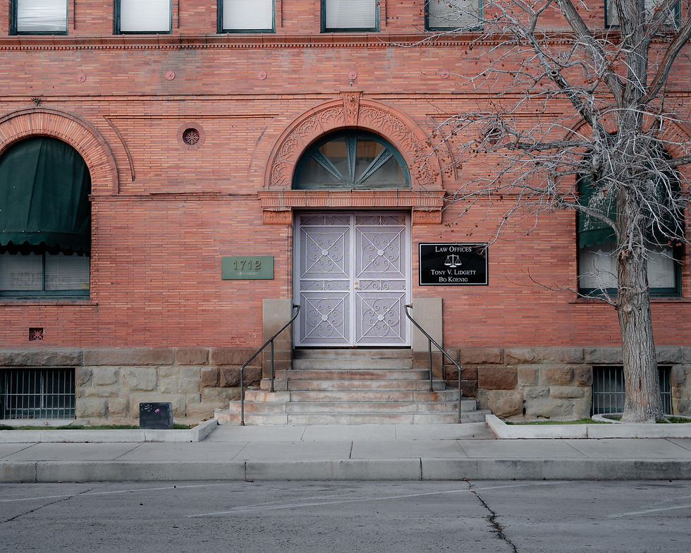The image shows the entrance to a historic red-brick building with arched windows and a central door framed by stone steps and handrails