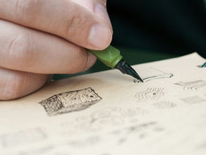 Hand drawing abstract sketches with a green fountain pen on beige paper. Close-up of fingers and detailed ink patterns.