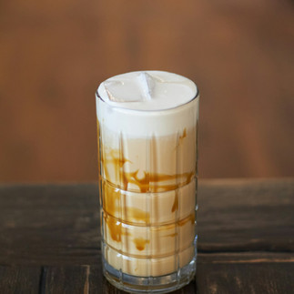 Coffee with caramel, milk, and cold foam in a glass