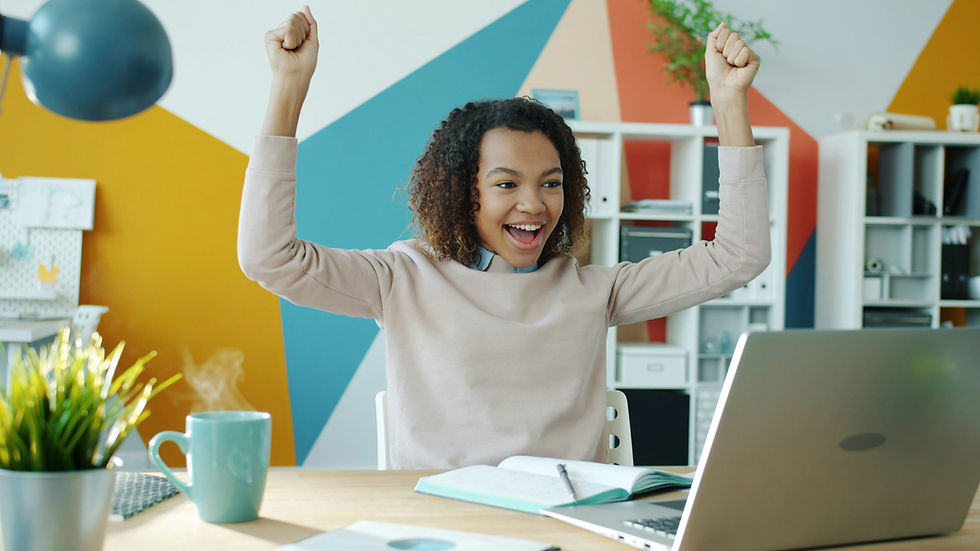 Girl celebrating while looking at a laptop, representing creating a winter break rhythm and maintaining routines at home.
