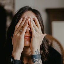 Woman covering her face while experiencing emotional distress.