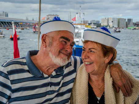 elderly husband and wife wearing white and blue sailor hats on vacation