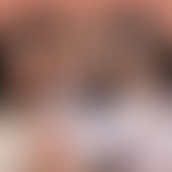 Three women smiling joyfully, embracing each other. Background features a warm, terracotta wall. One wears stripes, others in pastels. Warm mood.