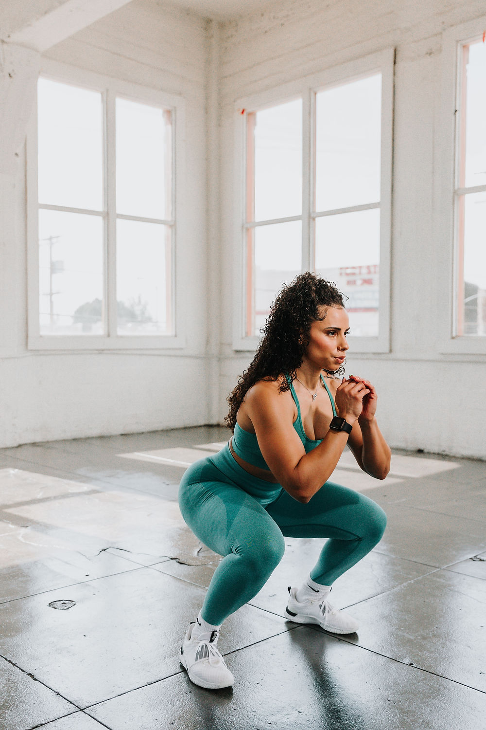 Woman in exercise space doing a bodyweight squat. 