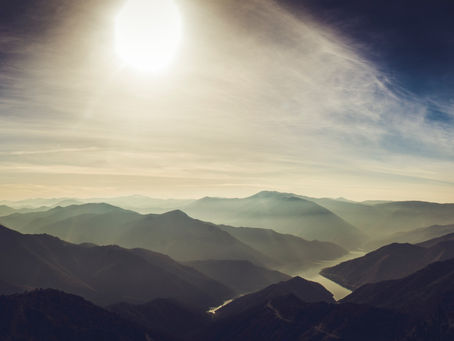 Mountain tops, clouds, and sun rays streaming down from the top