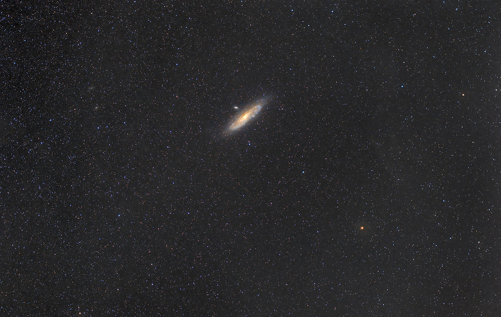 Star-filled night sky with a bright spiral galaxy glowing gold at center, surrounded by countless blue-white stars.