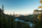 Eastern Sierra mountain landscape with pine trees, a winding river, and distant hills under a clear blue sky. The scene is serene and peaceful.