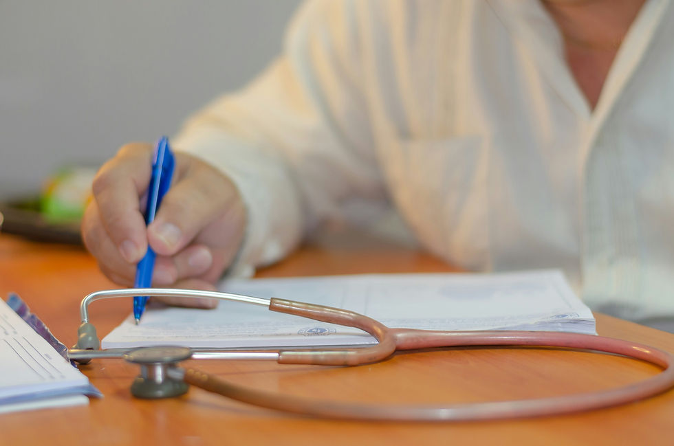 Image of hand with pen writing in notebook.  Stethoscope in foreground.