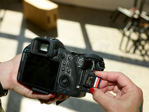 Podcast stüdyosunda kamera ile çekim yapılırken elde tutulan profesyonel fotoğraf makinesi