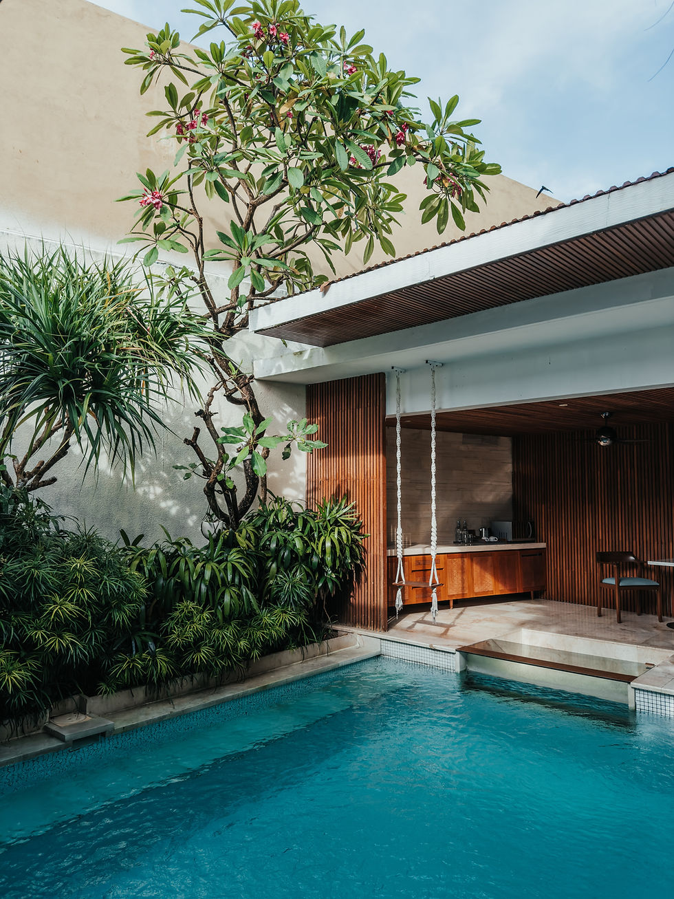 A serene backyard oasis featuring a refreshing pool, lush green foliage, and a cozy outdoor kitchen, perfect for relaxing and entertaining.