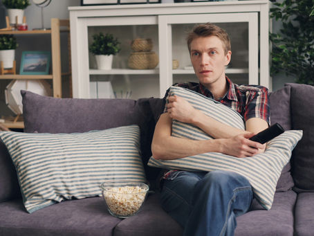 personne assise sur un sofa qui regarde la télévision