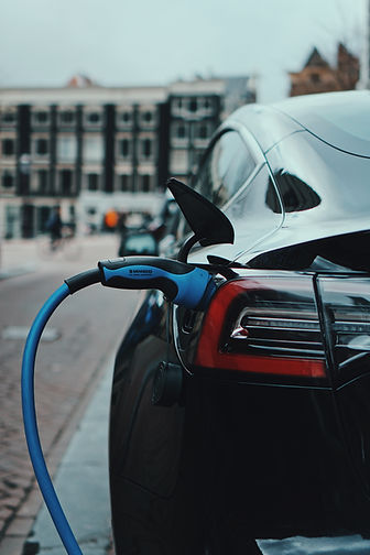 Blue electric charging cable plugged into a silver car parked outdoors