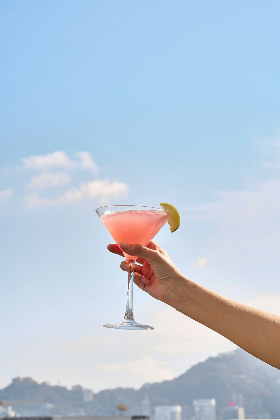 Person holding a colorful martini in the air