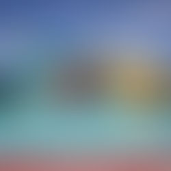 Colorful water slides and a clear pool under a blue sky. The slides are yellow, blue, and red, creating a playful and inviting scene.