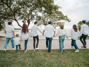 A large family holding hands, looking over towards the sea.