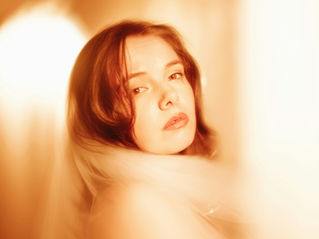 Vrouw met sluier kijkt melancholisch in een warme gloed. Zachte gele en oranje tinten in de achtergrond. Illustratie passend bij het thema microdosing met de Golden Teacher. Geen tekst zichtbaar.