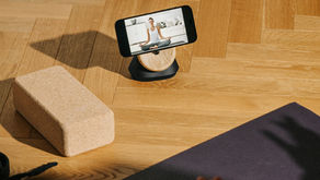 Online yoga class on smartphone with yoga mat, yoga block and yoga strap on hardwood floor