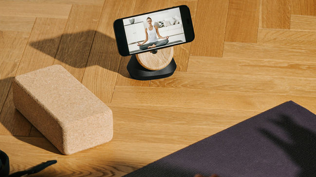 Online yoga class on smartphone with yoga mat, yoga block and yoga strap on hardwood floor