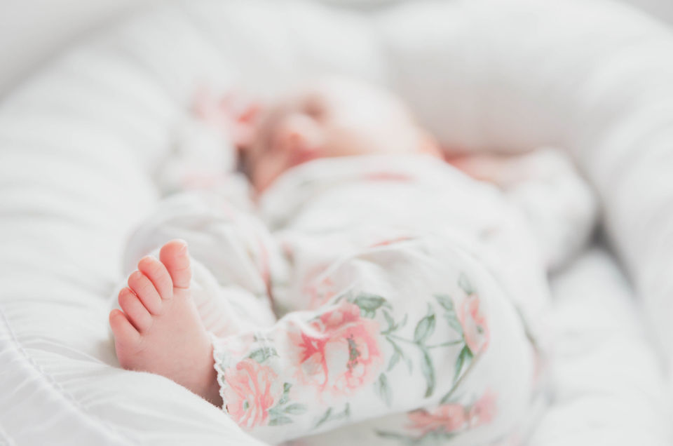 Newborn Photography by Blake Ferguson depicts a Sleepy Baby in a Cradle with Flower Pyjamas in Ontario, Canada.