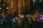 Night street scene with colorful hanging lights, busy road, and people walking. A person in a green shirt with a smiley face stands out.