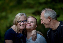 Image by Nathan Anderson; Woman with arms around teenage son. Man looking at the two and all are smiling.