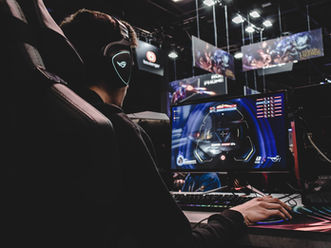 Person playing a video game on a computer while wearing headphones, illustrating the connection between ADHD and gaming addiction.