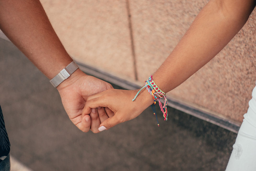Two people holding hands and one with friendship bracelets