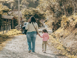 Una mujer caminando con un niño pequeño en un pueblo.