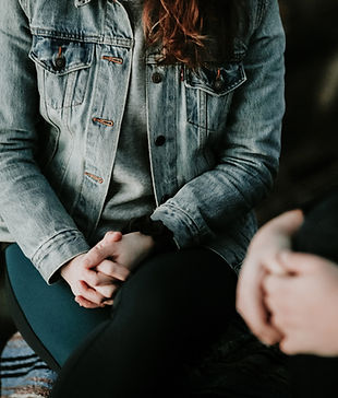 Body of a woman sat down holding her hands