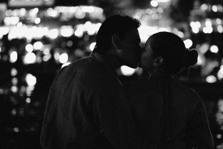 A couple shares a romantic kiss under the soft glow of city lights in a beautifully blurred background.