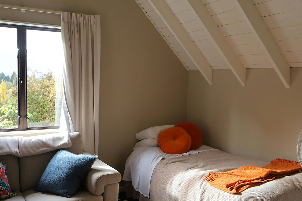 Habitación acogedora y bien distribuida con una ventana que ofrece una vista natural, complementada con detalles en colores cálidos y una decoración sencilla.