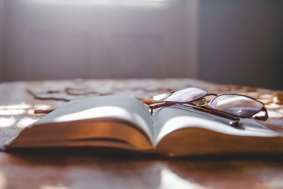 Eyeglasses on a book with sunlight shining through, symbolizing reflection and preparing for the return to school after winter break.