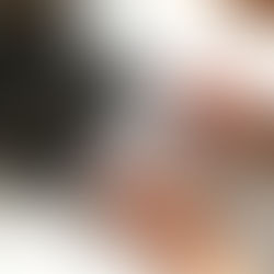 Hands with dark nails typing on a silver laptop in bright sunlight on a white table, creating a focused, professional mood.