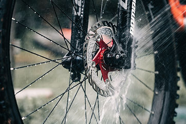 Bike wheel being cleaned with water spray, Fahrradbremsen, close-up view outdoors.