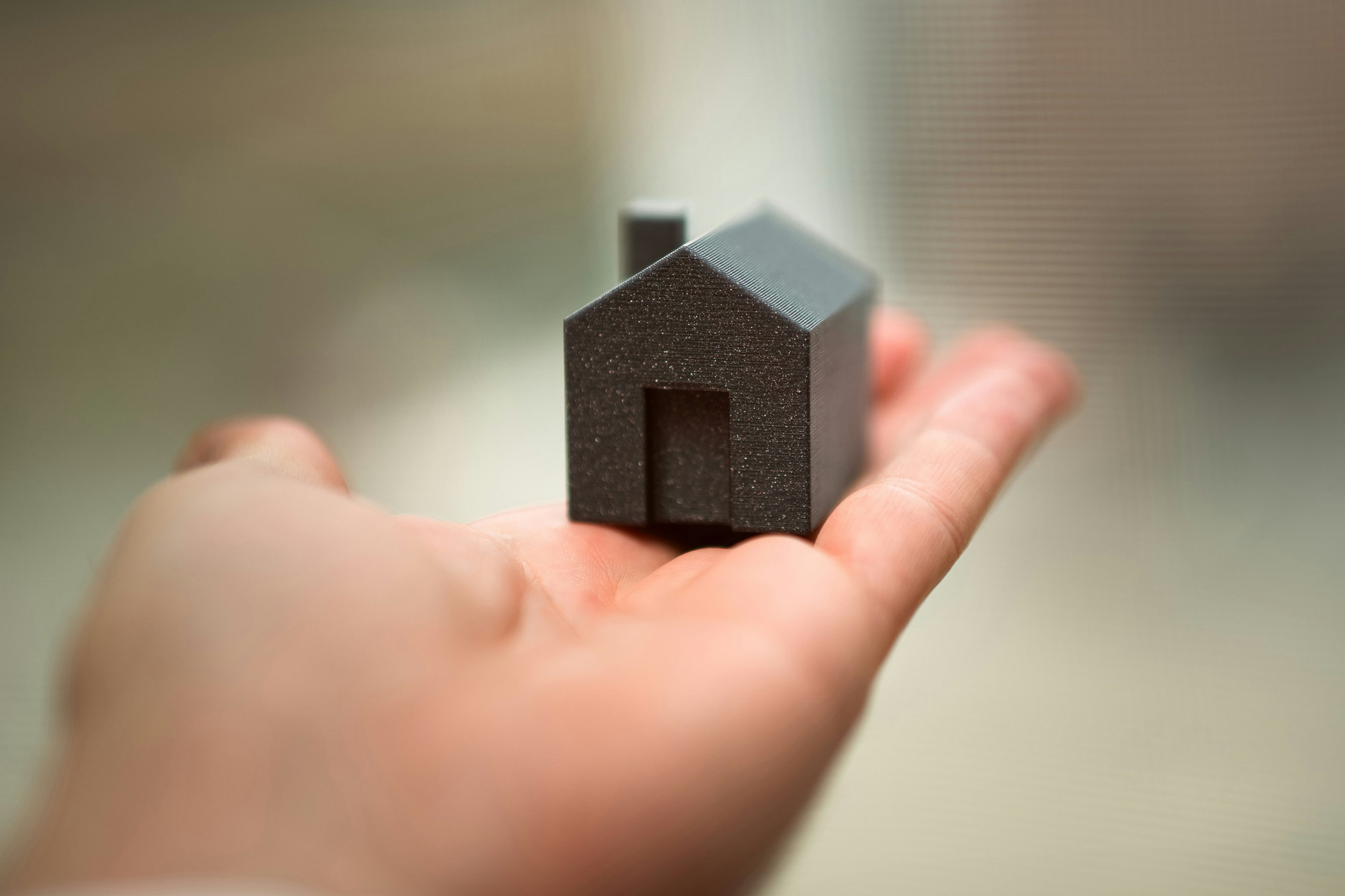 Small model house held in an open palm