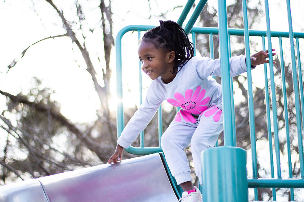 Smiling girl in a white and pink outfit on a slide.