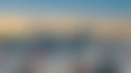 Manchester City skyline with modern skyscrapers under a gradient orange to blue sunset. Text includes "Hilton" and "Clayton Hotel." Calm mood.