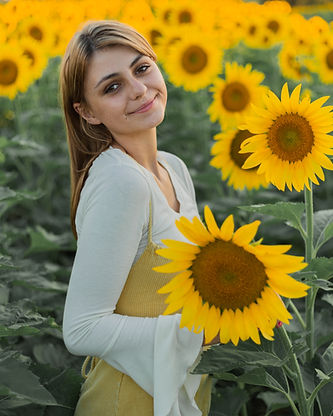 Young person with long hair smiles in sunflower field