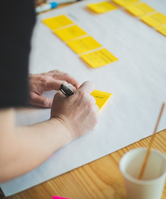 A woman writes on a sticky note ready to put it in a post-it strategy map