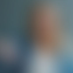 Woman with blond hair in a denim shirt gives a thumbs-down gesture, appearing displeased. Grey background adds a neutral tone.