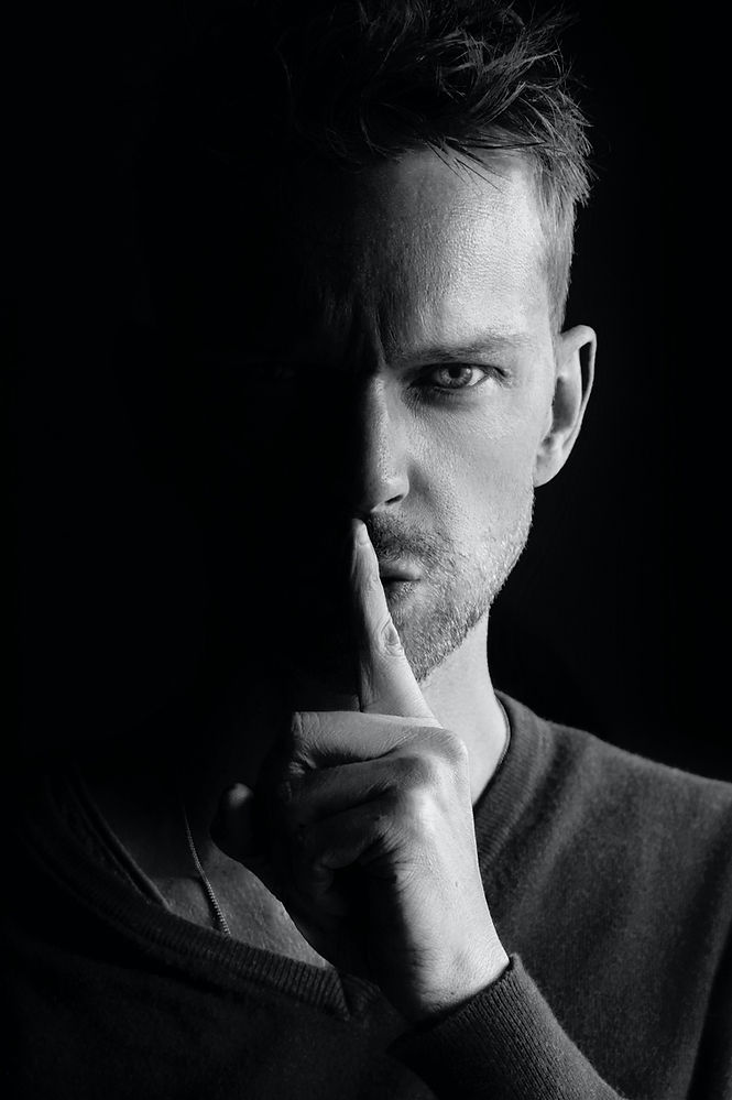 Man with dramatic lighting,gesturig "shhh!" to represent direct marketing as a secret weapon. Image by Sammy Williams