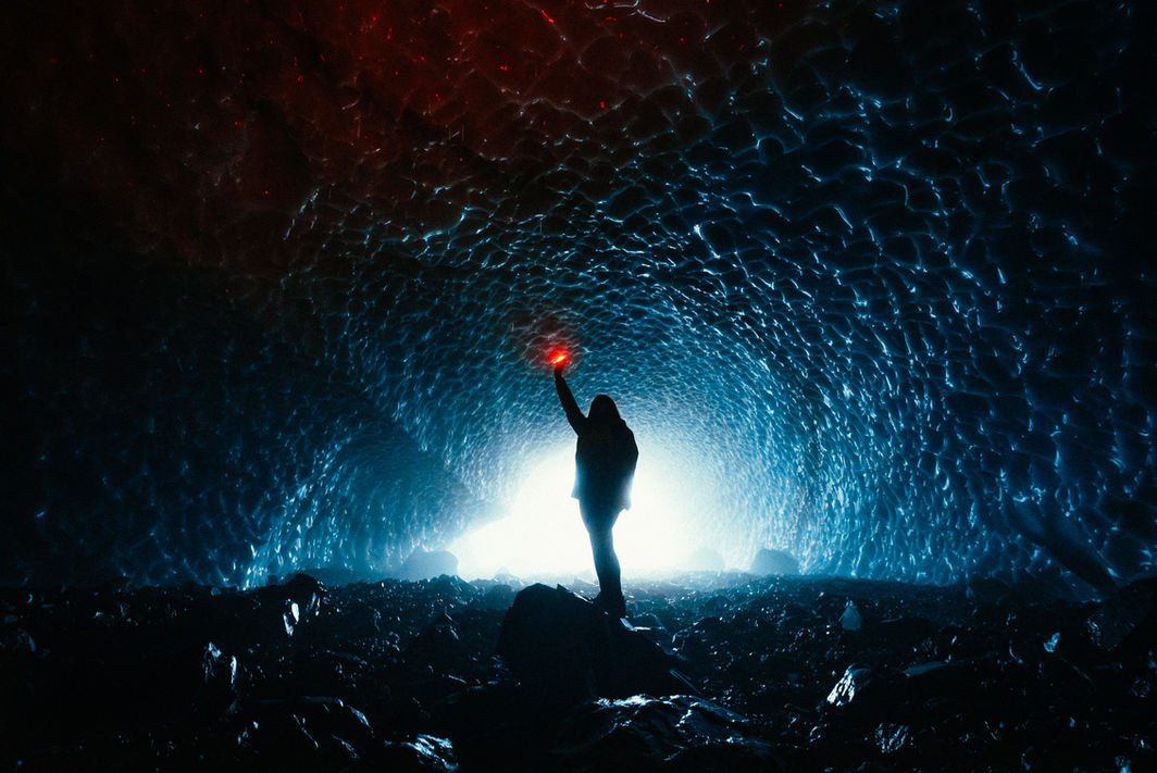 Aventuriero con una torcia in mano in una caverna di ghiaccio illuminata in Argentina.